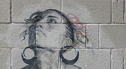 一面混凝土砌块墙，墙上贴着一幅小麦图案，画的是一个仰望天空的女人